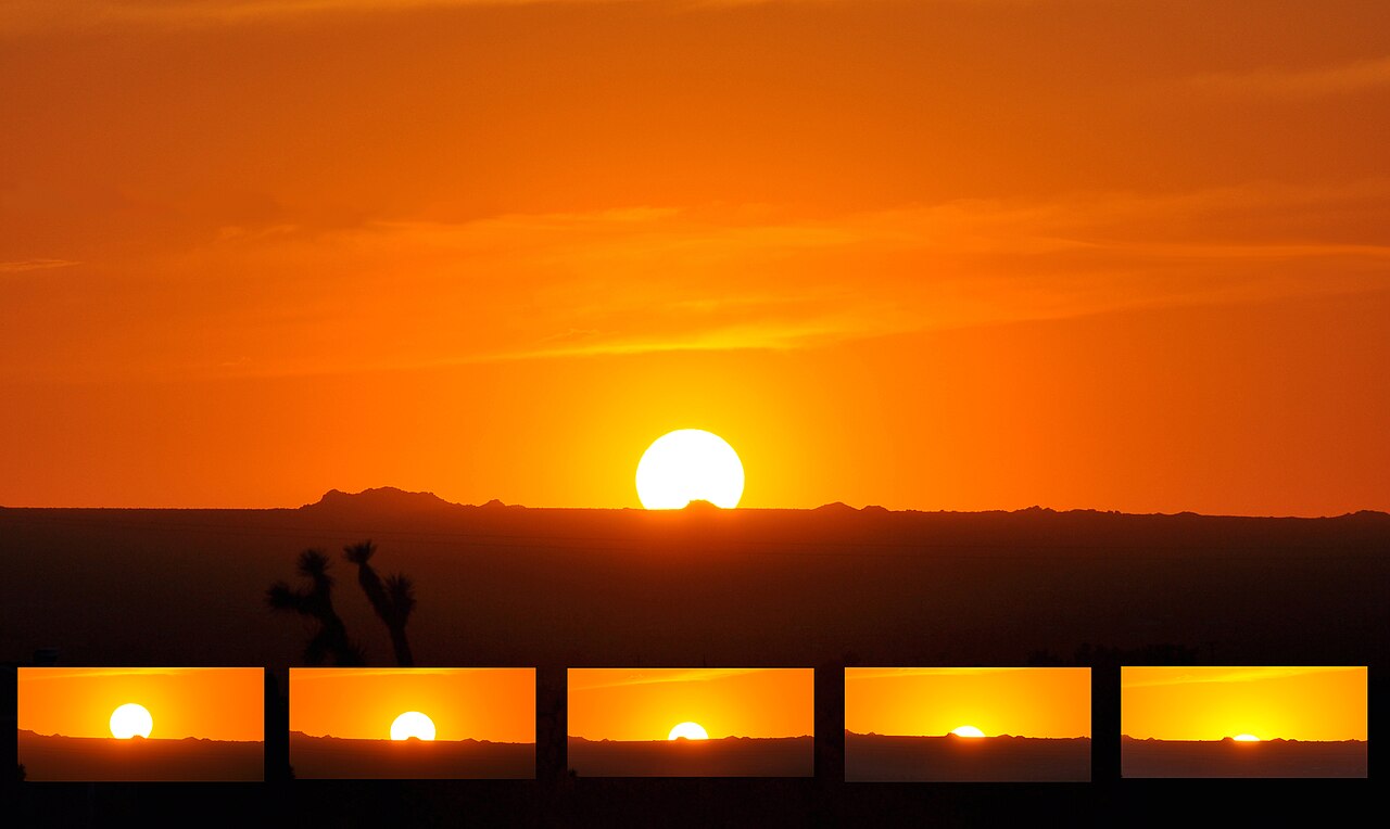 A vivid orange and red sunset over the horizon with a blue sky above